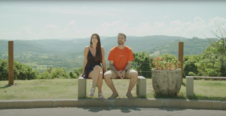 Cena do documentário Bitcoin Brasil com entrevistas e gráficos sobre criptomoedas.